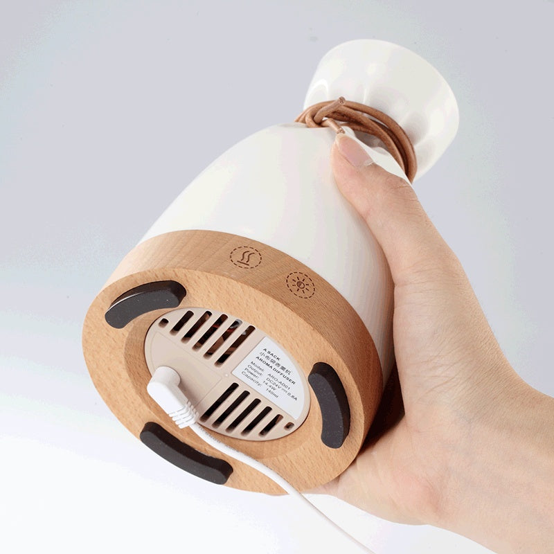 Wood Aromatherapy Desk Lamp Humidifier Aromatherapy Machine with a user holding the base and power cord.