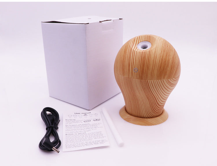 Household aromatherapy humidifier with wooden design, USB power supply, and user manual beside it.